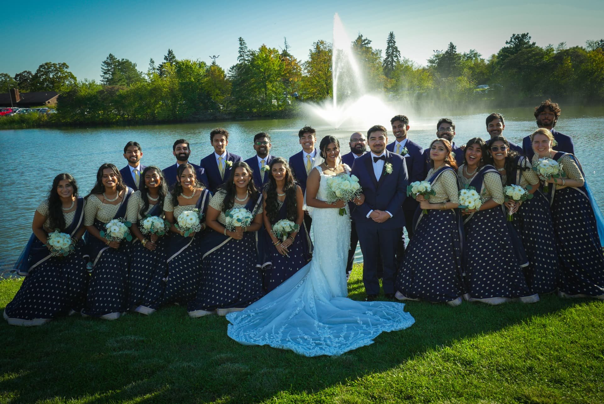 Bride and groom by the lake fountain with their wedding party