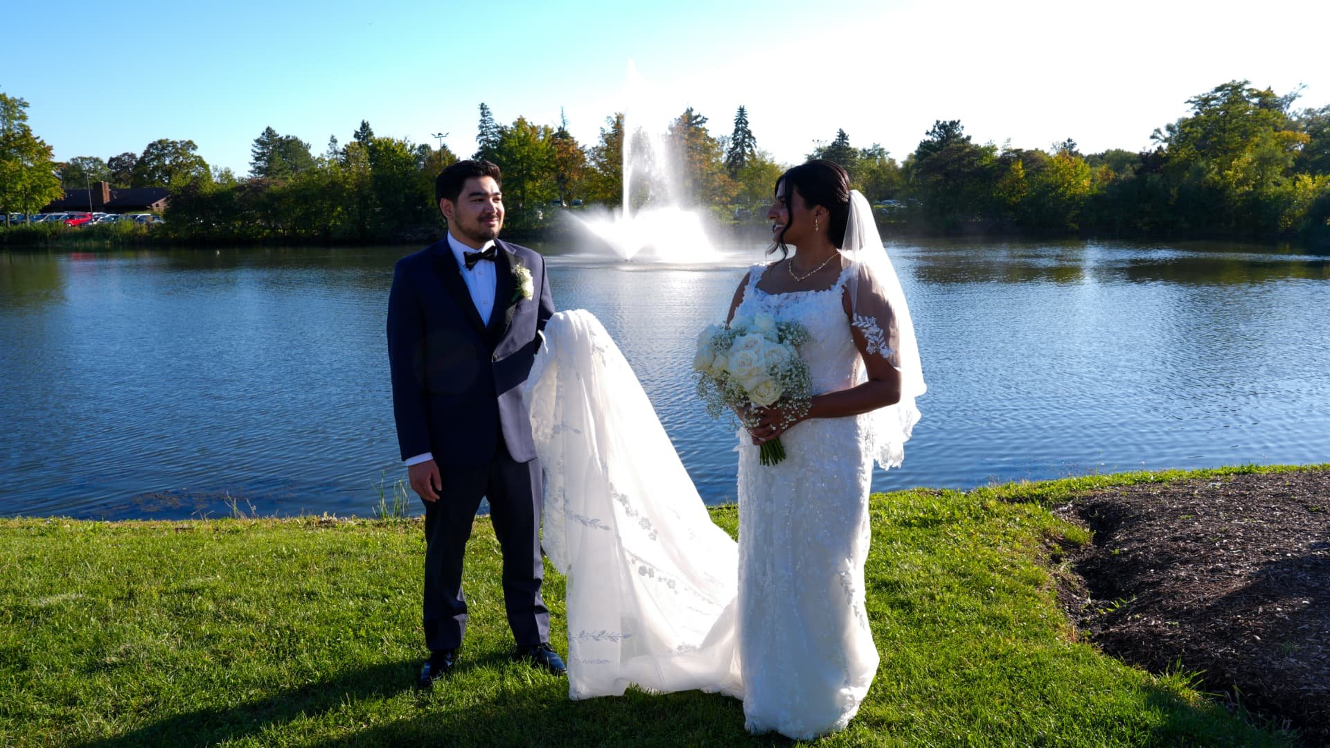 Bride and groom by the lake fountain with their wedding party